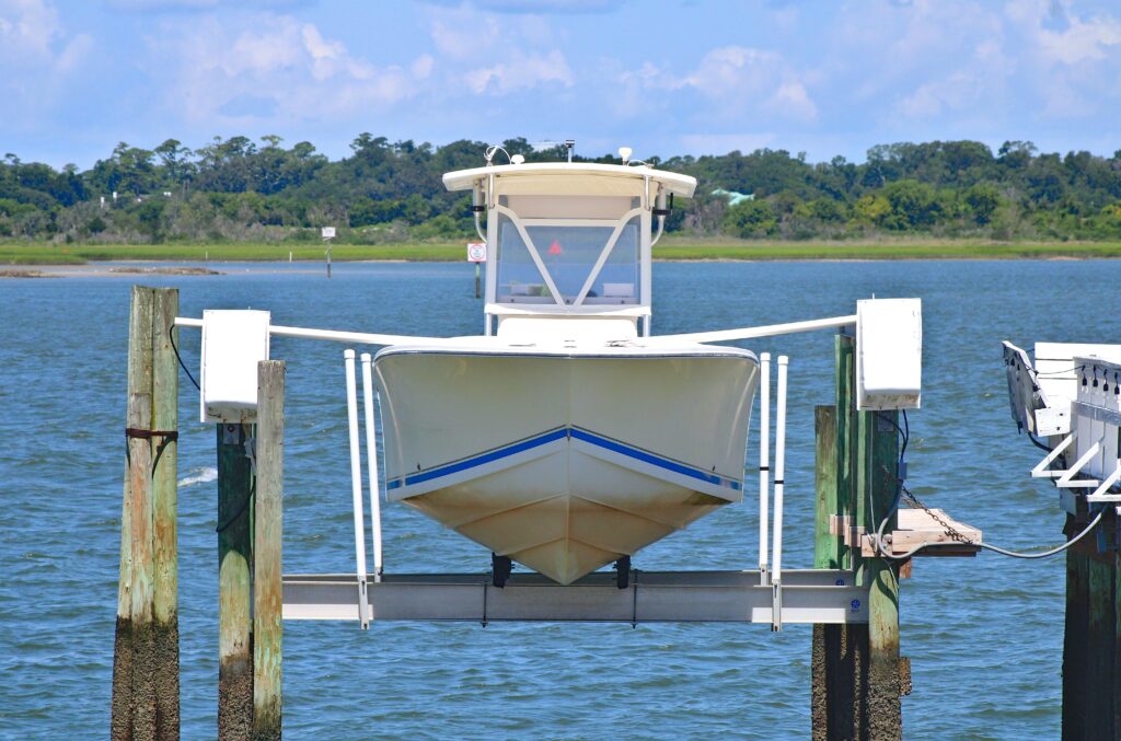 White boat lifted on dock with scenic waterway and lush greenery in the background.